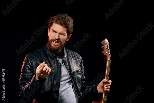 A man with a guitar in his hands leather jacket music performance rock star modern style dark background