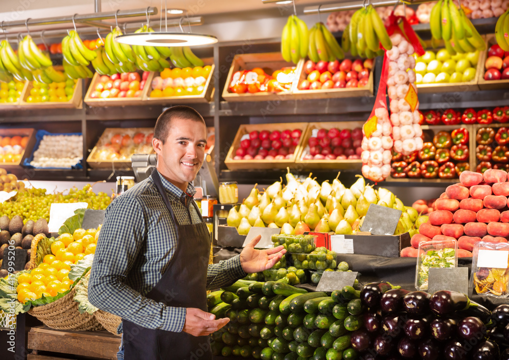 Portrait of friendly male shop assistant standing in front of the counter of a vegetable shop