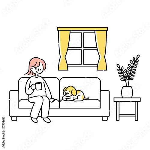 リビングのソファーに座って犬と一緒にくつろぐ女性