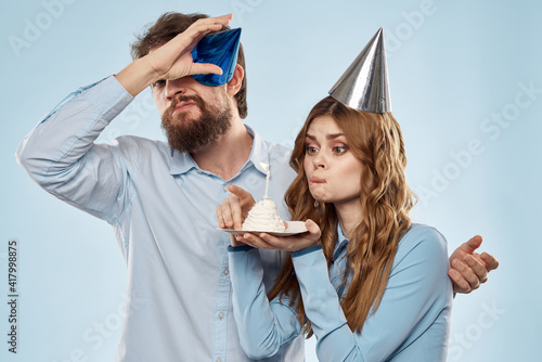 Cheerful man and woman with cake in a plate corporate party blue background