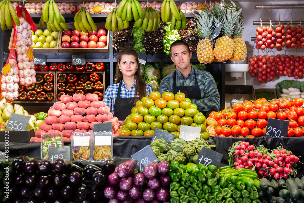 Cheerful male and female shop assistants in vegetable shop