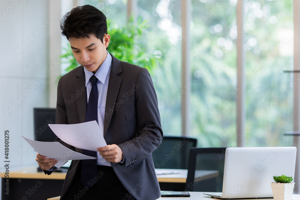 Glad Asian manager working with papers in office Glad Asian manager working with papers in office
