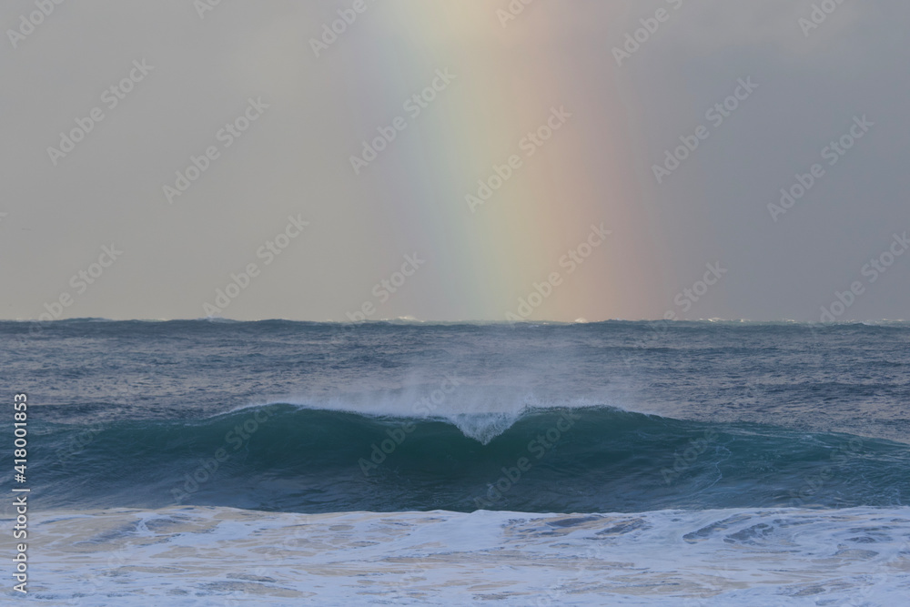 A stunning Vivid Rainbow formed over the Pacific Ocean close to where a large surfing competition is held in Chiba, Japan. There are large waves breaking onto the beach. It's close to Tokyo