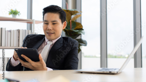 Confident Asian entrepreneur using tablet in office