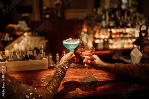 Canvas Print Hand of a happy loving couple with cocktail glasses, celebrating valentines day at the bar