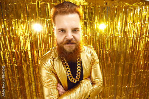 Obraz na plátně Serious angry man aggressively looking at you standing arms folded against shiny golden background