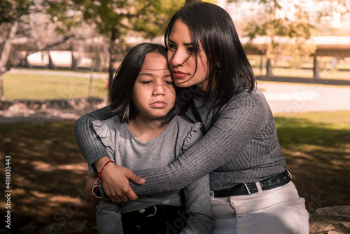 Young mother comforting her daughter outside at the park.
