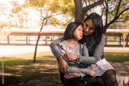 Latin mother consoling her sad daughter outside.