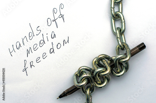 a fountain pen wrapped in an iron chain on sheets of white paper with the inscription hands off media freedom the concept of freedom of speech