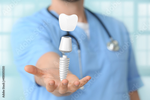 Male dentist with digital model of tooth implant in clinic, closeup photo