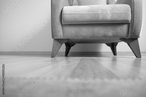 Black and white photo of single seat and minimalism. Old vintage and retro style single seating chair standing on wooden floor and its legs made of wooden material. photo