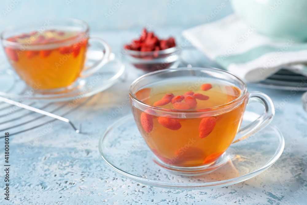 Glass cups of hot tea with goji berries on color background Glass cups of hot tea with goji berries on color background