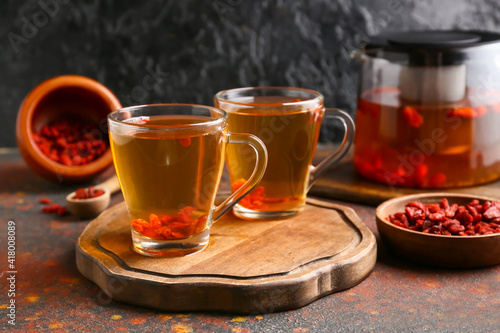 Glass cups of hot tea with goji berries on grunge background