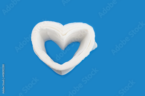 heart shape created from toilet paper on light blue background, Hygiene concept,