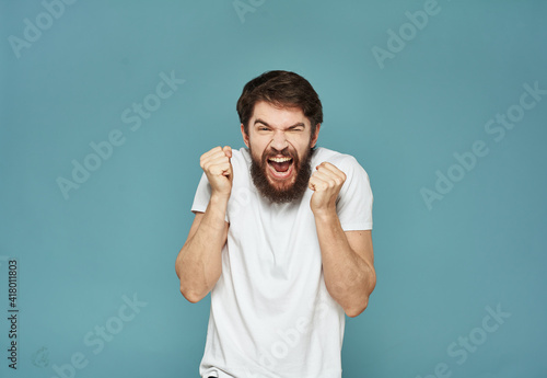 A successful man in a white T-shirt clenched his hands into a fist on a blue background