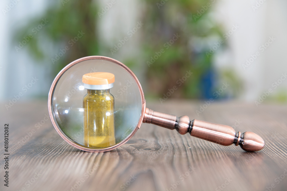 A medical vaccine or drug observed under a magnifying glass A medical vaccine or drug observed under a magnifying glass