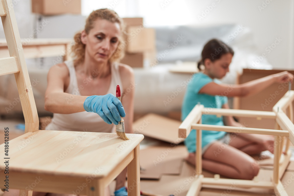 Mother and daughter painting and assembling furniture in new apartment, moving in and being hardworking. Mother and daughter painting and assembling furniture in new apartment, moving in and being hardworking.