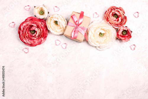 Festive romantic background with peony flowers, gift and hearts on light marble. Border top down composition with copy space.