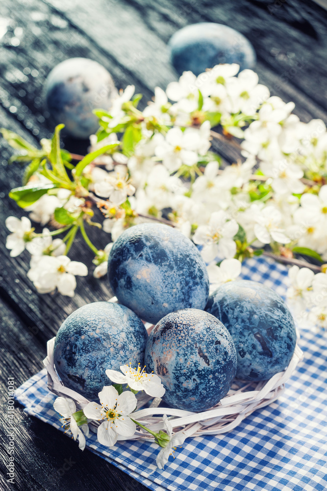 Easter blue marble eggs in a white bucket with cherry flower on the black wooden table Easter blue marble eggs in a white bucket with cherry flower on the black wooden table