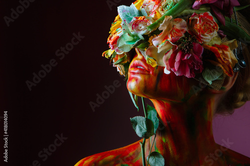 A model girl whose head is decorated with a headdress of fresh flowers that covers her eyes