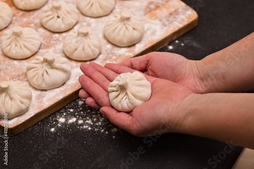 Freshly molded traditional Georgian khinkali from dough with minced meat and spices on the chef's palms.