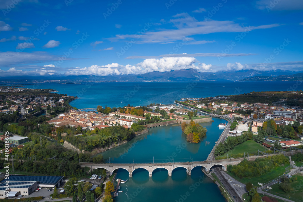 Italian town on the lake. Peschiera del Garda, Italy. Aerial view of the resort town on Lake Garda. Small town on the water against the background of water and high mountains top view.