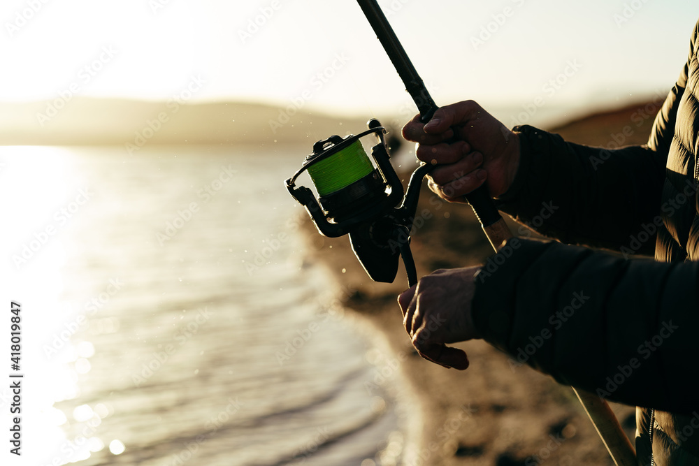 Fototapeta premium Fisherman hands holding fishing rod close up