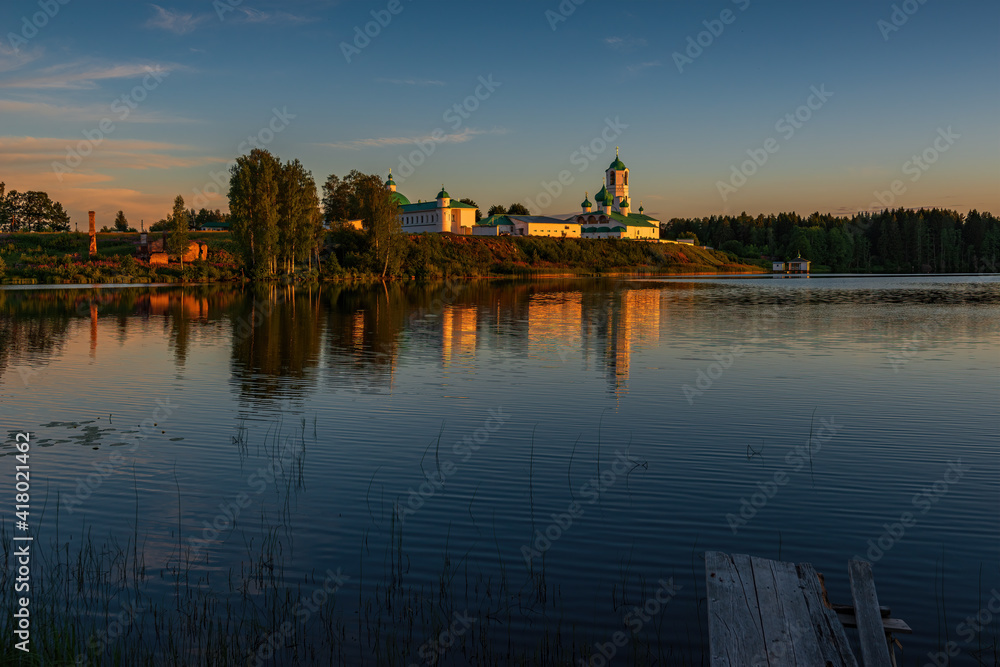 The monastery is located in a picturesque place on the high shore of the Roshchinsky lake, clear sky and evening sunset. Holy Trinity Alexander Svirsky Monastery in the Leningrad region.