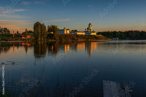 The monastery is located in a picturesque place on the high shore of the Roshchinsky lake  clear sky and evening sunset. Holy Trinity Alexander Svirsky Monastery in the Leningrad region.
