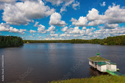 Roshchinsky lake in the sun and curly clouds, beautiful nature near the walls of the monastery. Holy Trinity Alexander Svirsky Monastery in the Leningrad region, known for architectural monuments.
