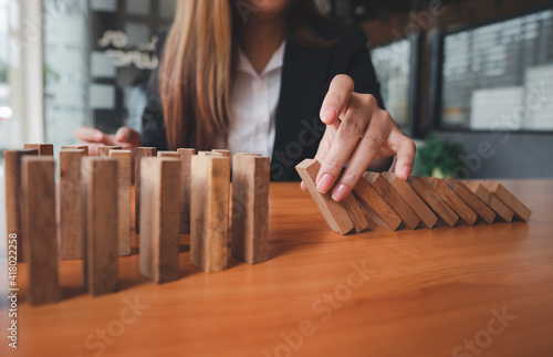 Businesswoman hand stopping the domino wooden effect concept for business and risk.