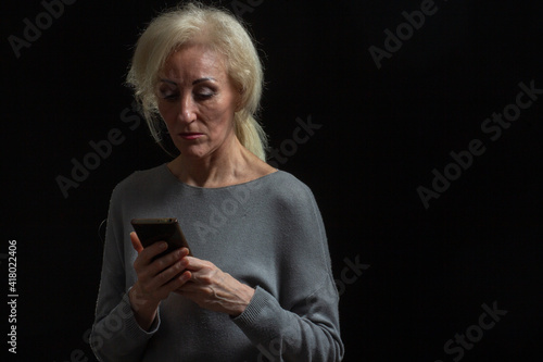 Classic portrait of elderly blonde woman in Studio on black background