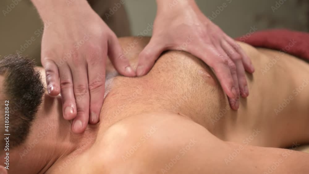 Close-up massage of the pectoral muscle to the athlete the client is doing a male masseur Close-up massage of the pectoral muscle to the athlete the client is doing a male masseur