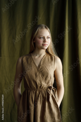 Beautiful young girl in a linen dress on a fabric background. Test shooting in the studio with a cloth.
