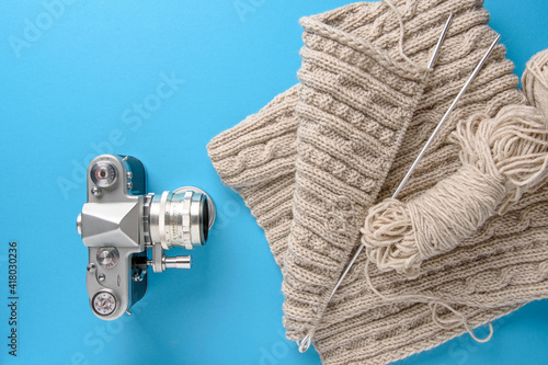 Knitting flatley. A horizontal collage of knitwear  skeins of yarn  knitting needles and a vintage camera on a bright background. Copy the space.