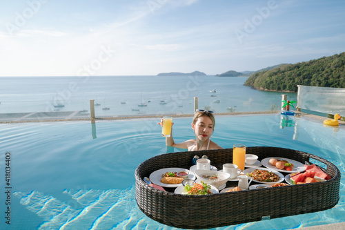 Happy woman relax with floating breakfast in swimming pool villa hotel resort.