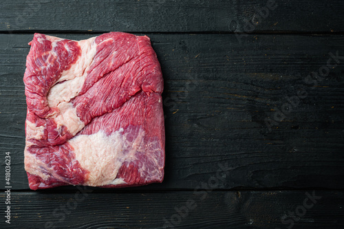 Raw piece of marble beef brisket, on black wooden table background, top view flat lay, with copy space for text