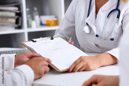 Female doctor hand hold silver pen and showing pad. Physical agreement form signature, disease prevention, ward round reception, consent contract sign, prescribe remedy, healthy lifestyle concept