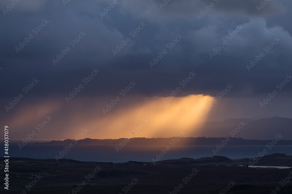 Rays of light at sunrise with cloudy and rainy weather. Scotland, UK.