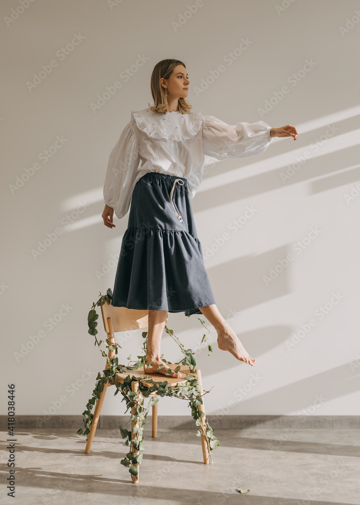 Woman standing barefoot on a wooden chair with legs tied with green twigs  with leaves, making a step. Stock Photo | Adobe Stock