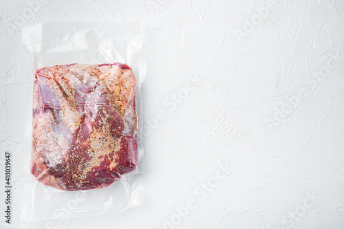Snack cross cut, raw beef brisket meat,with ingredients for smoking making sealed ready for sous vide cooking, on white stone background, top view flat lay, with copy space for text