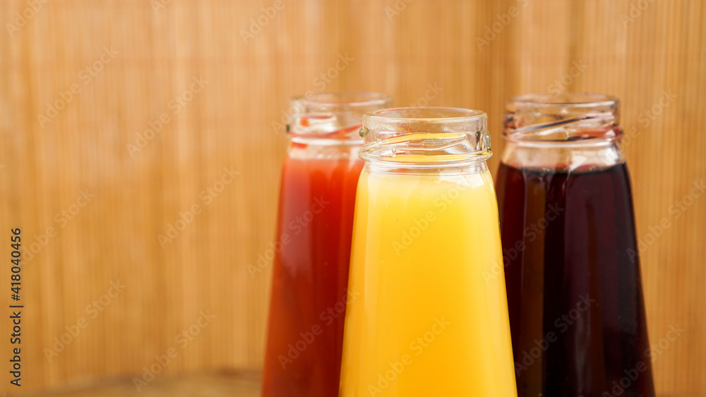 Glass bottles of fresh healthy juice on wooden background. Multi-colored juices. Glass bottles of fresh healthy juice on wooden background. Multi-colored juices.