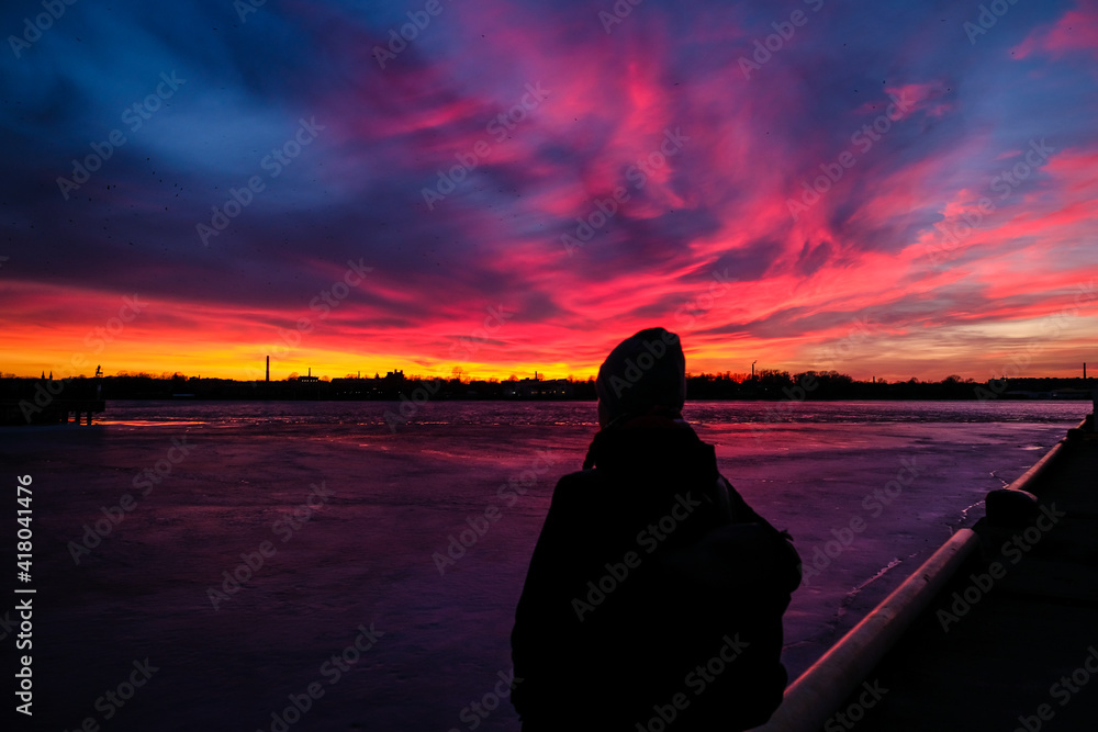 Amazing red sunrise sky with clouds over black silhouette of girl. Selective focus