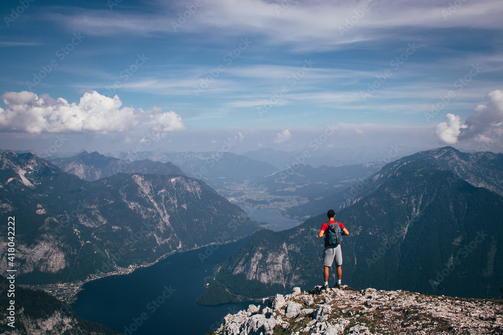 man with a backpack takes in Austrian nature and a hallstatter see from Mount Krippenstein. A sense of relaxation and freedom. The sporty type enjoys the feeling of victory over this mountain