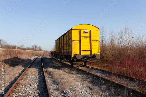 Abandoned yellow train wagon, weathered and rusty, on an old train tracks