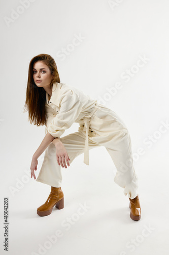 fashionable woman leaned forward white jumpsuit studio modern style isolated background