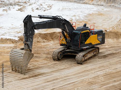 Excavator loads dump truck in the sand quarry. Big excavator machine