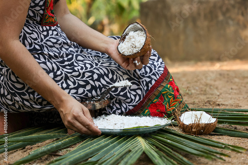 Woman hand taking fresh grated coconut to prepare homemade thick coconut milk Kerala India , Indian Fresh shredded coconut ingredient in Indian curry. vegan non dairy health drink.
