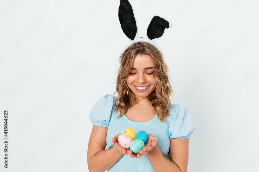 Lovely blonde young woman wearing Easter bunny ears holding colored eggs Lovely blonde young woman wearing Easter bunny ears holding colored eggs