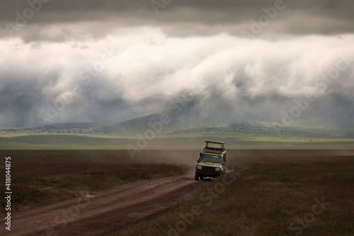 Safari car on a road in Ngorongoro National Park, Tanzania with beautiful clouds in background. Wild nature of Africa. © danmir12